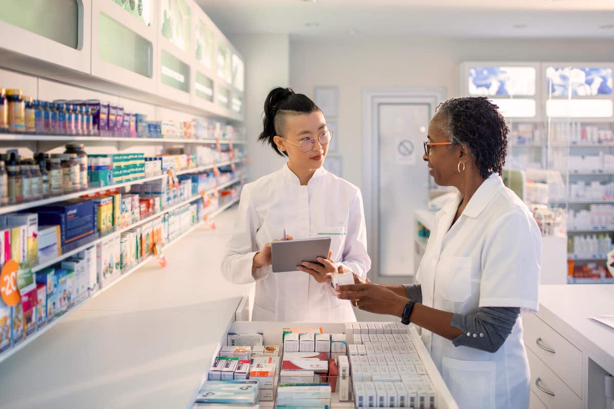 Pharmacists discuss medications while consulting their device