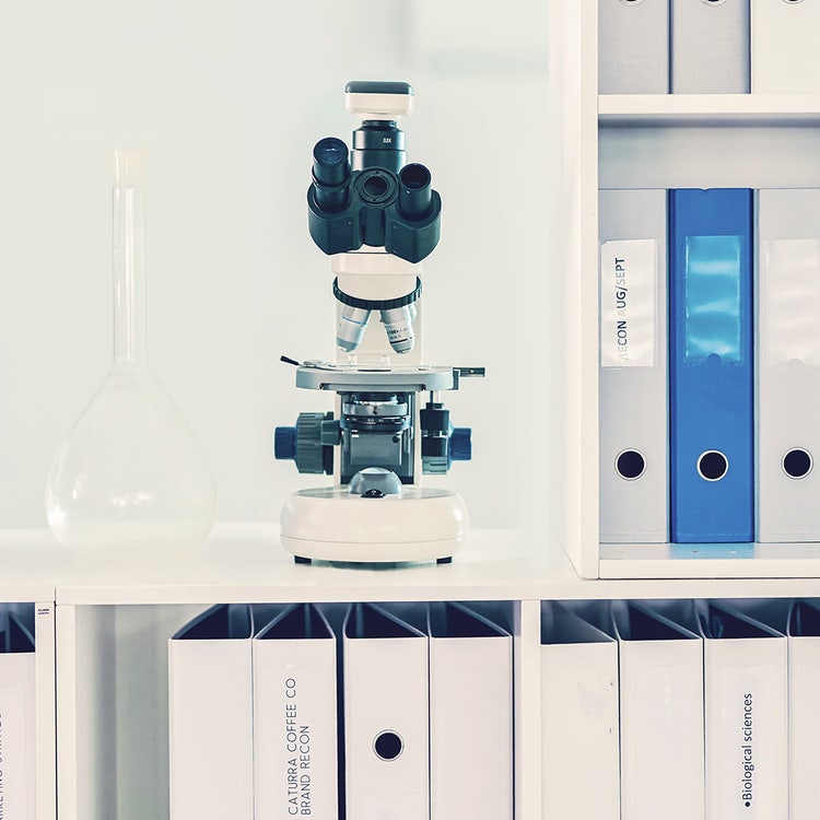 White microscope on white table with white folders and white background in lab